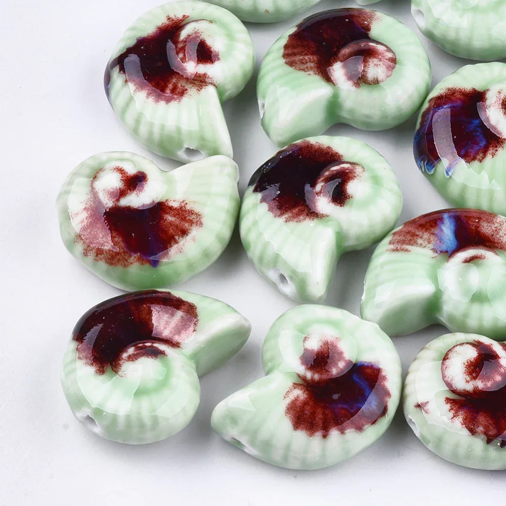 Porslinspärla - Snäcka, Ljusgrön / Brun med blått 1 styck Hilmas Pyssel